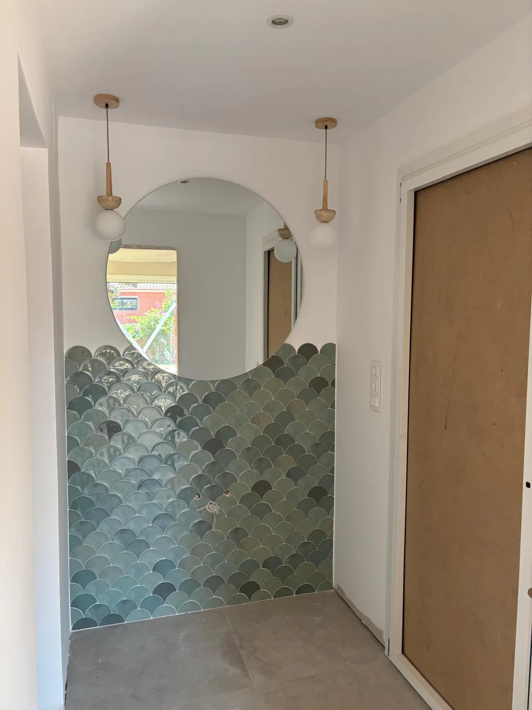 Baño reformado con azulejos verdes y espejo redondo en Casa en Premià de Dalt